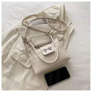 Détail du sac bandoulière en cuir blanc cassé avec boucle nœud et poignée nouée