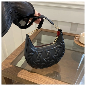 Detail of black crescent shoulder bag with geometric texture and gold zipper closure
