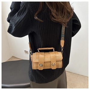 Brown cylinder bag with white stitching and retro ethnic style wide shoulder strap
