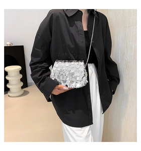 Detailed close-up of a silver sequin crossbody bag with chain strap on a model