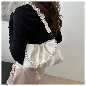 Detail of white pleated shoulder bag with elegant pearl chain and satin texture finish