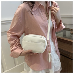 Dettaglio borsa a tracolla bianca in pelle grana litchi con nappa e hardware dorato