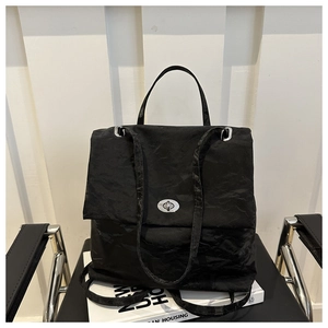 Close-up of black wrinkled leather bag featuring a silver oval twist-lock on a book