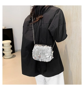 Detail of silver sequin crossbody bag with chain strap and reflective metallic finish