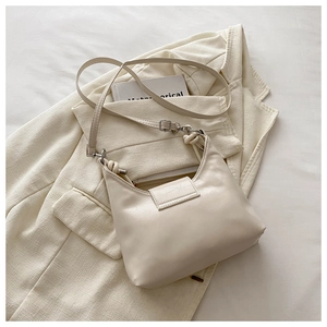 Détail du sac sous le bras demi-lune blanc cassé avec bandoulière nouée sur costume