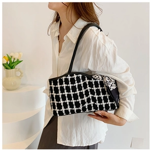 Detail of checkered shoulder bag with a black and white polka dot bow decoration