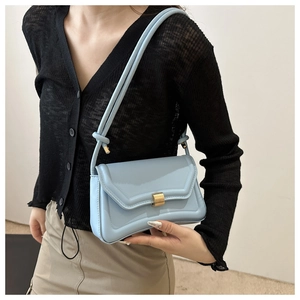 Detail of light blue underarm bag with gold metal clasp worn by a fashion model
