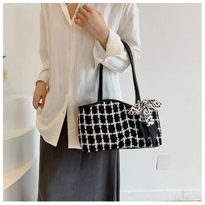 Detail of checkered tweed tote bag featuring black leather handles and leopard print ribbon