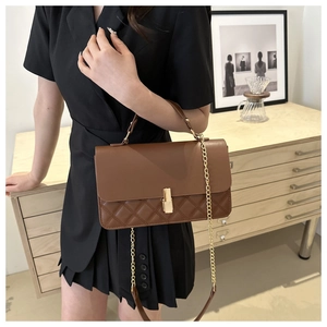 Detailansicht der braunen Steppledertasche mit goldenem Schloss und Kettenriemen am Modell