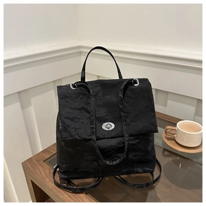 Close-up of black pleated texture bag with silver oval turn-lock on a wooden table