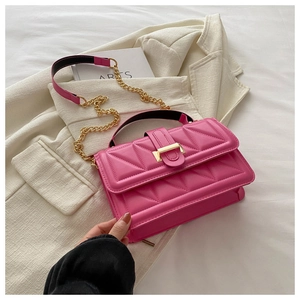 Detail of hot pink quilted crossbody bag with gold chain strap on a white blazer