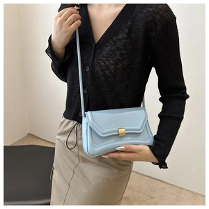Chic light blue mini saddle bag with golden buckle and slim strap worn by model