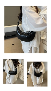 Detail of black crescent hobo bag with knotted shoulder strap and silver metal buckle