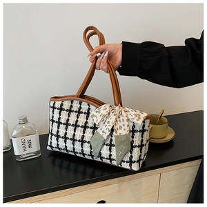 Close-up of black and white tweed chain tote bag with brown leather handles and silk bow