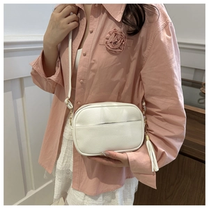 Dettaglio borsa a tracolla bianca con trama litchi e nappe decorative alla moda