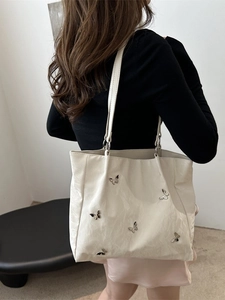 Chic cream bow bucket bag with silver butterfly charms shown on female model back
