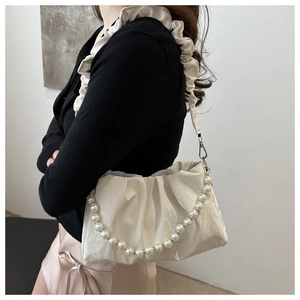 Close-up of pleated cloud bag with elegant pearl bead handle and ruffled shoulder strap