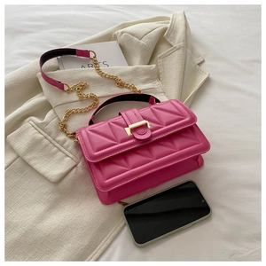 Detail of rose red crossbody bag with textured triangular patterns and gold metal clasp