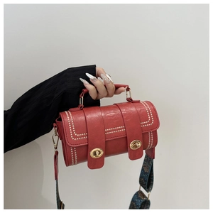 Detail of red leather baguette bag with dual metal locks and ethnic style woven strap