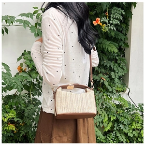 Detail of summer straw crossbody bag with brown leather trim and golden metal clasp
