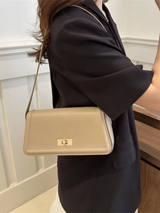 Khaki leather shoulder tote bag with gold twist clasp shown in a modern urban interior