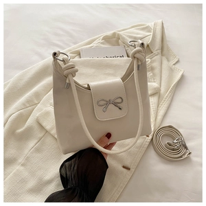 Détails du sac crème avec boucle nœud argentée et poignée avec décoration nouée