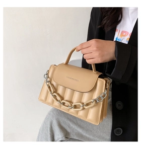 Close-up of cream quilted crossbody bag with chunky chain strap and vertical padding