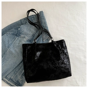Detail view of black crinkle patent leather tote bag with large capacity and slim straps