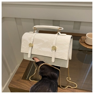 Detail of cream marble-textured crossbody bag with golden chain and metallic buckles