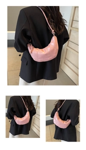 Detail of pink croissant bag showing vertical stitching and knotted shoulder strap detail