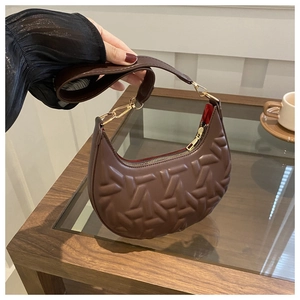 Detailed close-up of brown crescent bag featuring geometric embossed texture and gold hardware