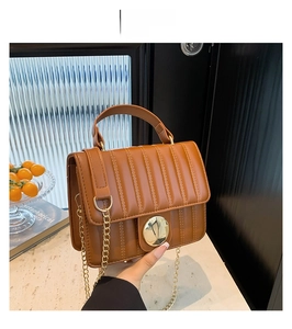 Detail of vertical quilted brown PU leather bag with golden metallic twist lock clasp