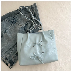 Macro detail of light blue tote bag with ribbon bow and crinkled PU leather texture