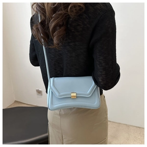 Back view of model wearing a light blue quilted leather saddle bag with gold metal buckle