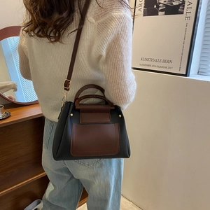 Detail of a color-block crossbody bag featuring black and brown faux leather panels