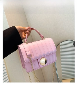 Detailed side view of pink quilted handbag with gold chain strap and metal buckle