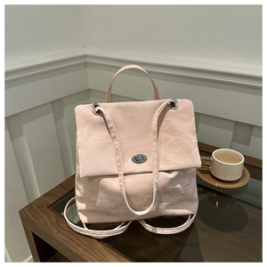 Detail of soft pink gathered fabric bag featuring a metallic silver twist lock closure