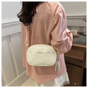 Dettaglio di una borsa a tracolla bianca minimalista con nappa e trama in pelle