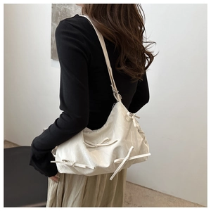 Detailed view of cream bow shoulder bag with pleated texture and soft PU leather finish