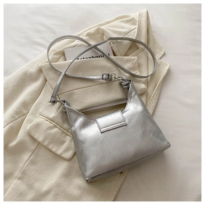 Gros plan du sac à bandoulière argenté avec texture métallique sur fond de tissu clair