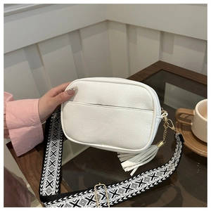 Borsa a tracolla bianca in pelle martellata con tracolla geometrica e nappa sul tavolo