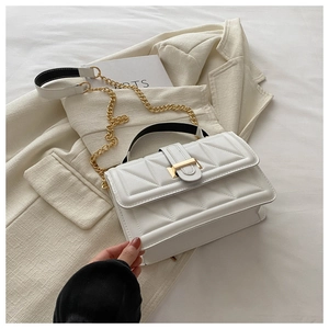 Detail of white quilted crossbody bag with gold chain strap and geometric textures