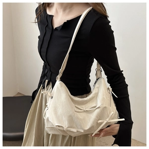 Detail of cream hobo bag showing multiple bow decorations and wrinkled leather texture