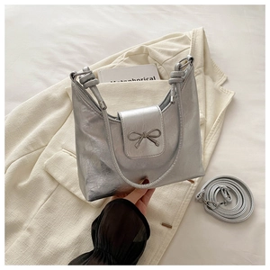 Détail du sac à main argenté en cuir froissé avec nœud métallique et deux bandoulières