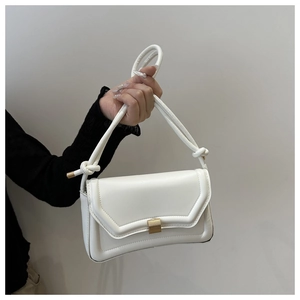 Detail of white PU leather saddle bag with gold square buckle and knotted handle