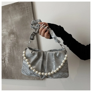 Dettaglio borsa in raso plissettato argento con elegante catena di grandi perle