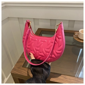 Detail of rose pink crescent underarm bag with geometric embossed texture and gold hardware