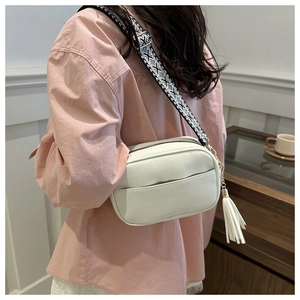 Close-up of white lychee leather crossbody bag with geometric woven wide shoulder strap