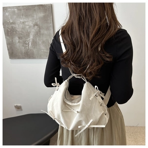 Detail of cream white backpack featuring 3D bow accents and soft wrinkled texture