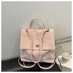 Close-up of light pink pleated bag with a silver metal twist lock on a black leather seat